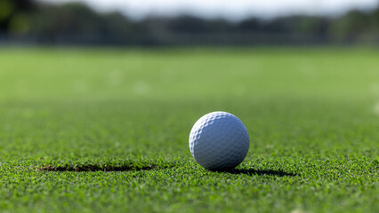 In the hole, White golf ball on green grass with golf hole, Golf ball ready to be shot, Golf ball close up on green grass in the hole, Top view.