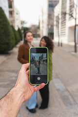 A close-up of a smartphone screen showing two coworkers posing for a picture in an office district. A moment of team bonding and workplace connection.