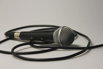 Concert microphone with audio cable, black with silver metal mesh. On a white background. Close-up. For recording vocals, singing performances, studio recording of podcasts and broadcasts