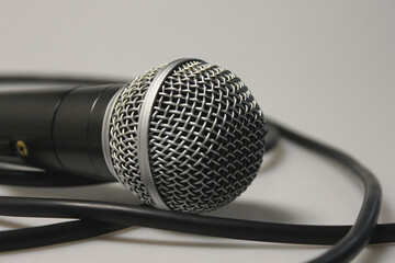 Concert microphone with audio cable, black with silver metal mesh. On a white background. Close-up. For recording vocals, singing performances, studio recording of podcasts and broadcasts