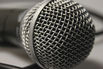 Concert microphone with audio cable, black with silver metal mesh. On a white background. Close-up. For recording vocals, singing performances, studio recording of podcasts and broadcasts
