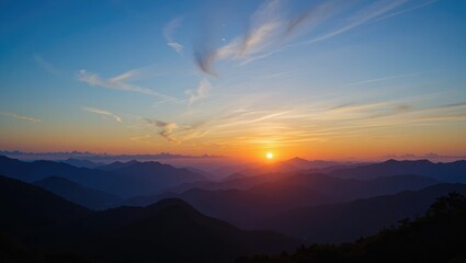 Obraz premium Stunning Sunset Over Layered Mountains with Colorful Sky and Soft Clouds in Tranquil Atmosphere