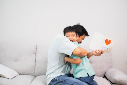 Asian boy give a gift card to his father, Dad and son embrass each other with love and happiness, Relationship in family concept.