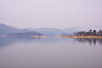 The rainy day scenery of Daecheong Lake is calm and beautiful. The mist and still waters reflect like a dream, and the lone tree on the island adds to the solitude. The distant mountains fade into the