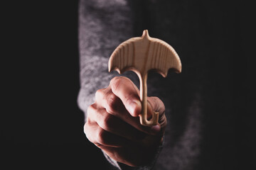 A man holds a small wooden umbrella in his hand.