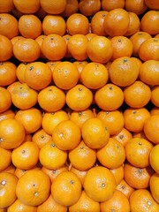 Top-down view of a neatly stacked display of fresh Sunkist oranges. Bright and vibrant citrus fruits arranged in an organized pattern, showcasing their natural texture and rich orange color.
