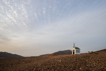 small cute white wooden chapel in a barren volcanic landscape. Sunrise, landscape shot of Ermita...