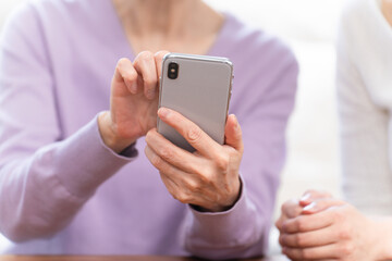 若い女性にスマートフォン操作を習うシニア女性