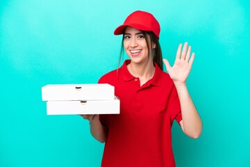Pizza delivery woman with work uniform picking up pizza boxes isolated on blue background saluting...