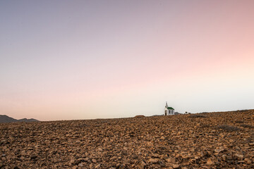 small cute white wooden chapel in a barren volcanic landscape. Sunrise, landscape shot of Ermita...