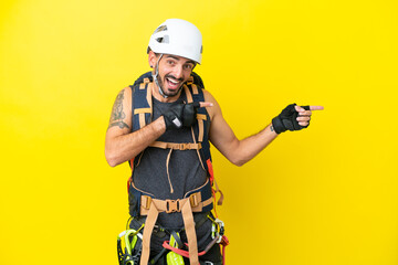 Fototapeta premium Young caucasian rock climber man isolated on yellow background surprised and pointing side