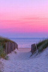 Fototapeta premium sandy beach path lined with wooden fences and dune grass leads to a calm ocean under a stunning pink and purple sunset sky. The tranquil scene evokes relaxation, serenity, and coastal beauty