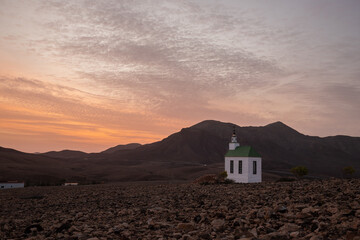 small cute white wooden chapel in a barren volcanic landscape. Sunrise, landscape shot of Ermita...