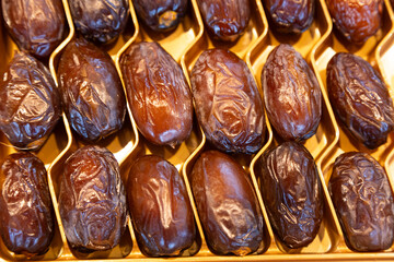 Premium dried dates with a glossy texture arranged in a golden tray. Perfect for food photography, organic produce, healthy eating concepts, and luxurious gift packaging.