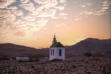 small cute white wooden chapel in a barren volcanic landscape. Sunrise, landscape shot of Ermita...