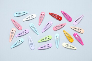 Different hair clips on grey background, flat lay