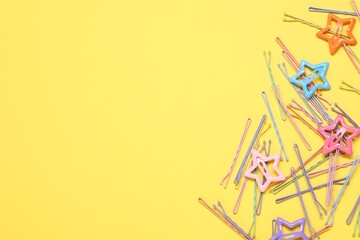 Colorful hair pins on yellow background, flat lay. Space for text