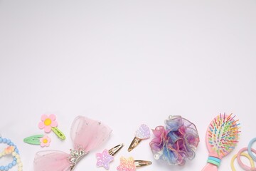 Different hair accessories and brush on light background, flat lay. Space for text