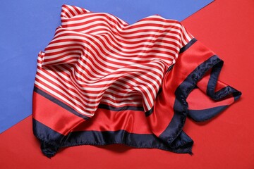 Beautiful striped scarf on color background, top view