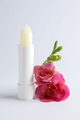 Lip balm and freesia flowers on white background, closeup