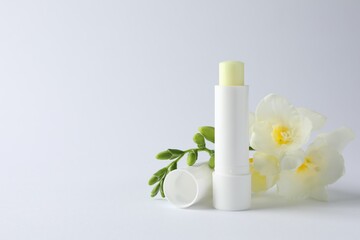 Lip balm and freesia flowers on white background, closeup. Space for text