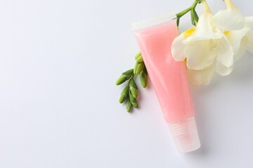 Lip balm and freesia flowers on white background, flat lay. Space for text