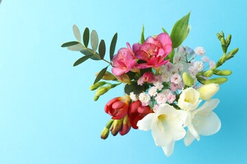 Bouquet of beautiful flowers on light blue background, top view. Space for text