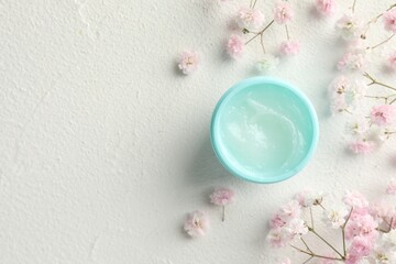 Moisturizing lip balm and gypsophila flowers on light textured table, flat lay. Space for text