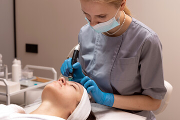 Skincare professional performing microneedling treatment on client in spa setting