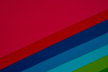 Vibrant layers of colored paper in shades of pink, red, blue, and green, creating a visually striking palette for artistic projects or crafts.