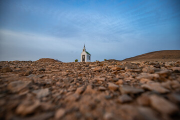 small cute white wooden chapel in a barren volcanic landscape. Sunrise, landscape shot of Ermita...