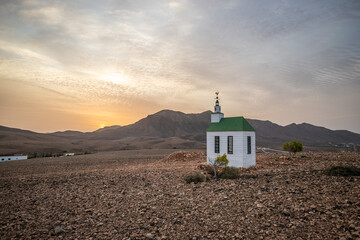 small cute white wooden chapel in a barren volcanic landscape. Sunrise, landscape shot of Ermita...