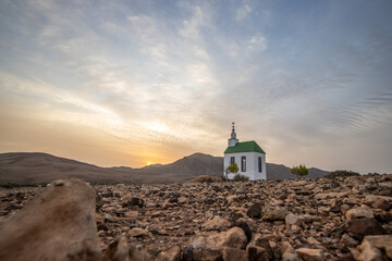 small cute white wooden chapel in a barren volcanic landscape. Sunrise, landscape shot of Ermita...