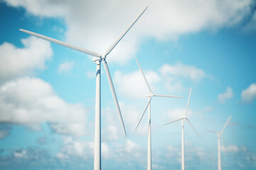 Fototapeta premium Wind turbines generating renewable energy against a bright blue sky with scattered clouds.