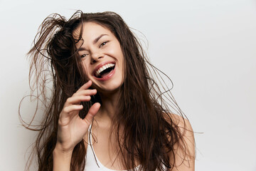 happy woman with messy hair, smiling joyfully against a white background, expressing carefree...