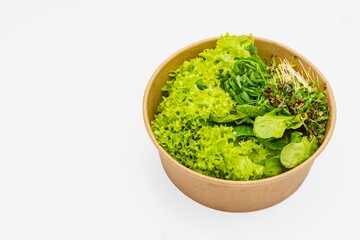 Fresh salad in a bowl on a white background. Close-up of fresh organic green salad with microgreens in a bowl. Healthy food.