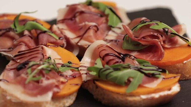 Sandwiches with slices of ham jamon iberico, fresh toast. Rotating on a black plate. Side view, close-up