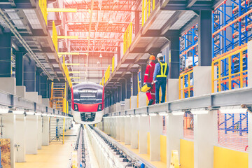 Electric train technician engineer with blueprints checking controls system for security functions in maintenance infrastructure plant of sky train, public transportation vehicle,Teamwork management