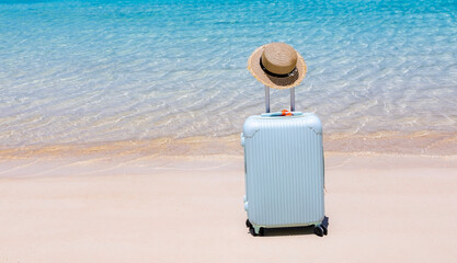 The blue luggage on the beach- summer travel concept