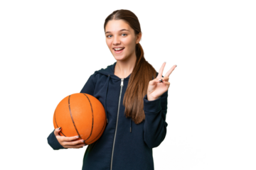 Teenager caucasian girl playing basketball over isolated background smiling and showing victory sign