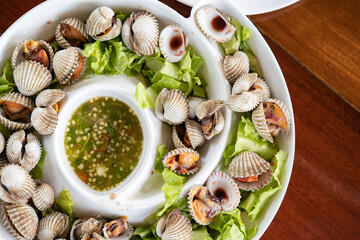 On the platter, there is cockle, juicy meat and veggies. Consume seafood sauce.