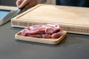 Raw Pork is prepared for Cook, It is on wood plate on black granite kitchen counter tabletop, shot by studio light. Clipping Paths.