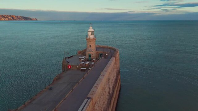 Lighthouse in Folkestone UK beach with ocean around in the sunset