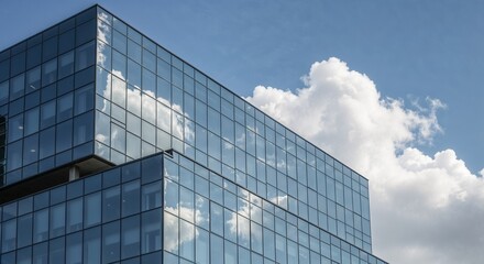 Reflective glass facade of modern office building with clouds in blue sky