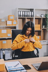 Asian SME business women use laptop computer checking customer order online shipping boxes at home....