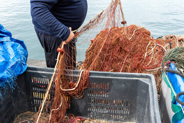 fisherman hands rolling up and preparing the fishing net.