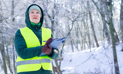 Eco volunteer. Female ecologist inspects trees. Forestry engineer works in winter. Inspector...
