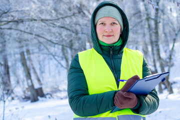 Eco volunteer. Female ecologist inspects trees. Forestry engineer works in winter. Inspector...