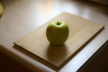 A green healthy apple on the wooden chopping board in the kitchen