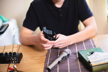 A teenager holds a microphone stand in his hands. He is assembling a mini-studio for recording...